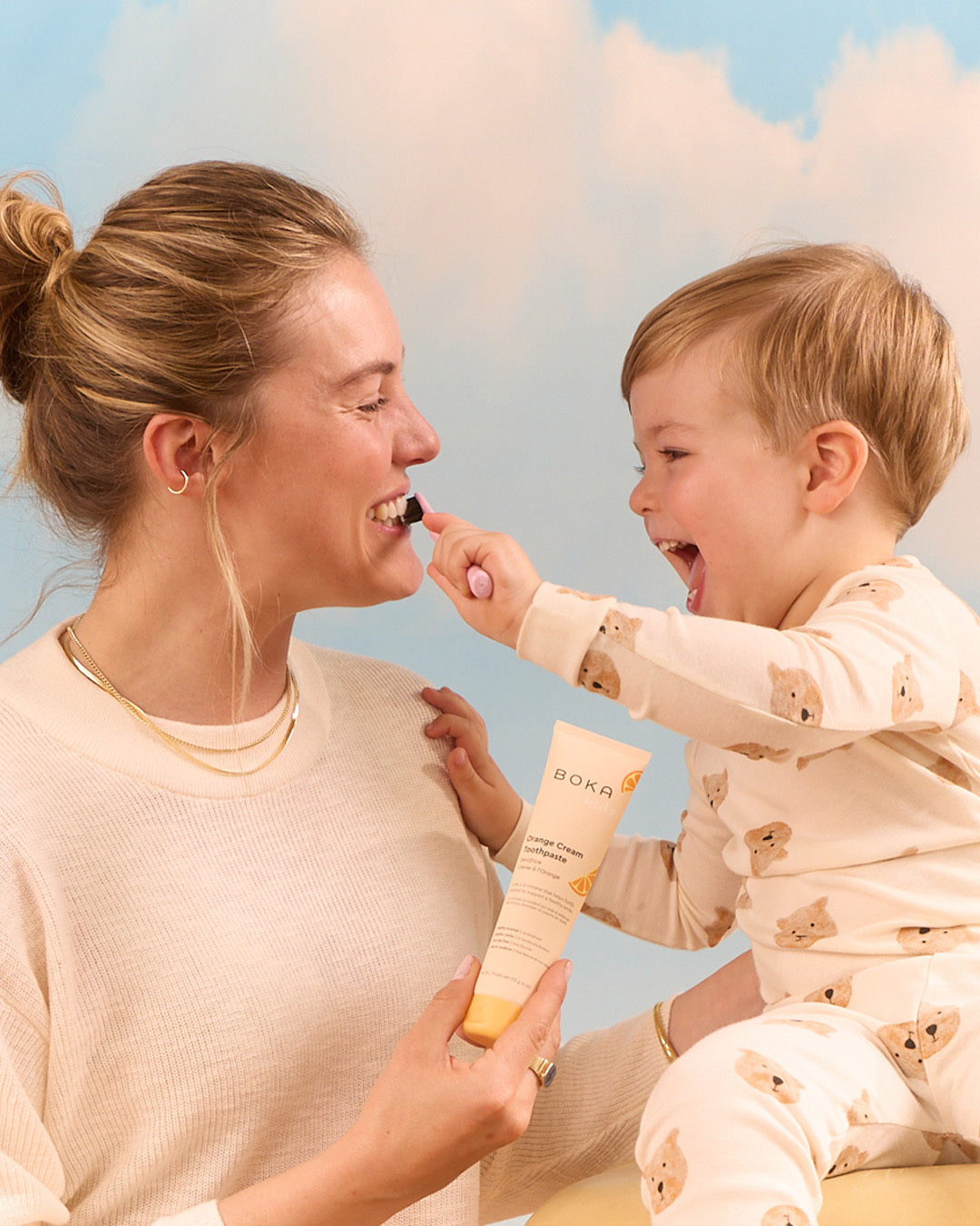Baby brushing woman's teeth
